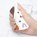 A calico cat coaster bent in a hand to show it is soft and flexible