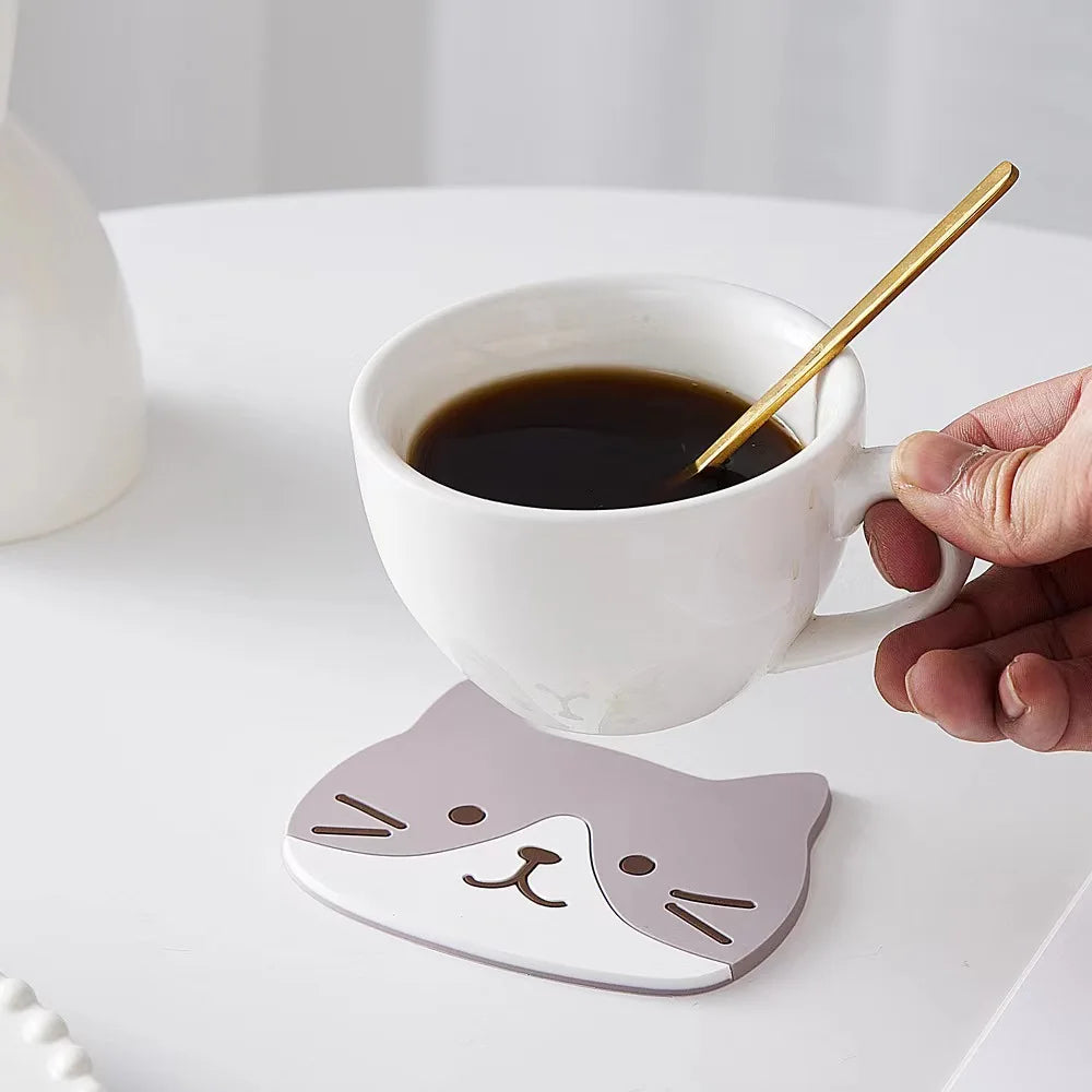 A grey-and-white cat coaster under a white coffee cup