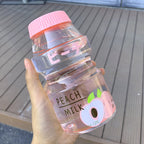 Clear peach fruit milk water bottle held in one hand to show its size