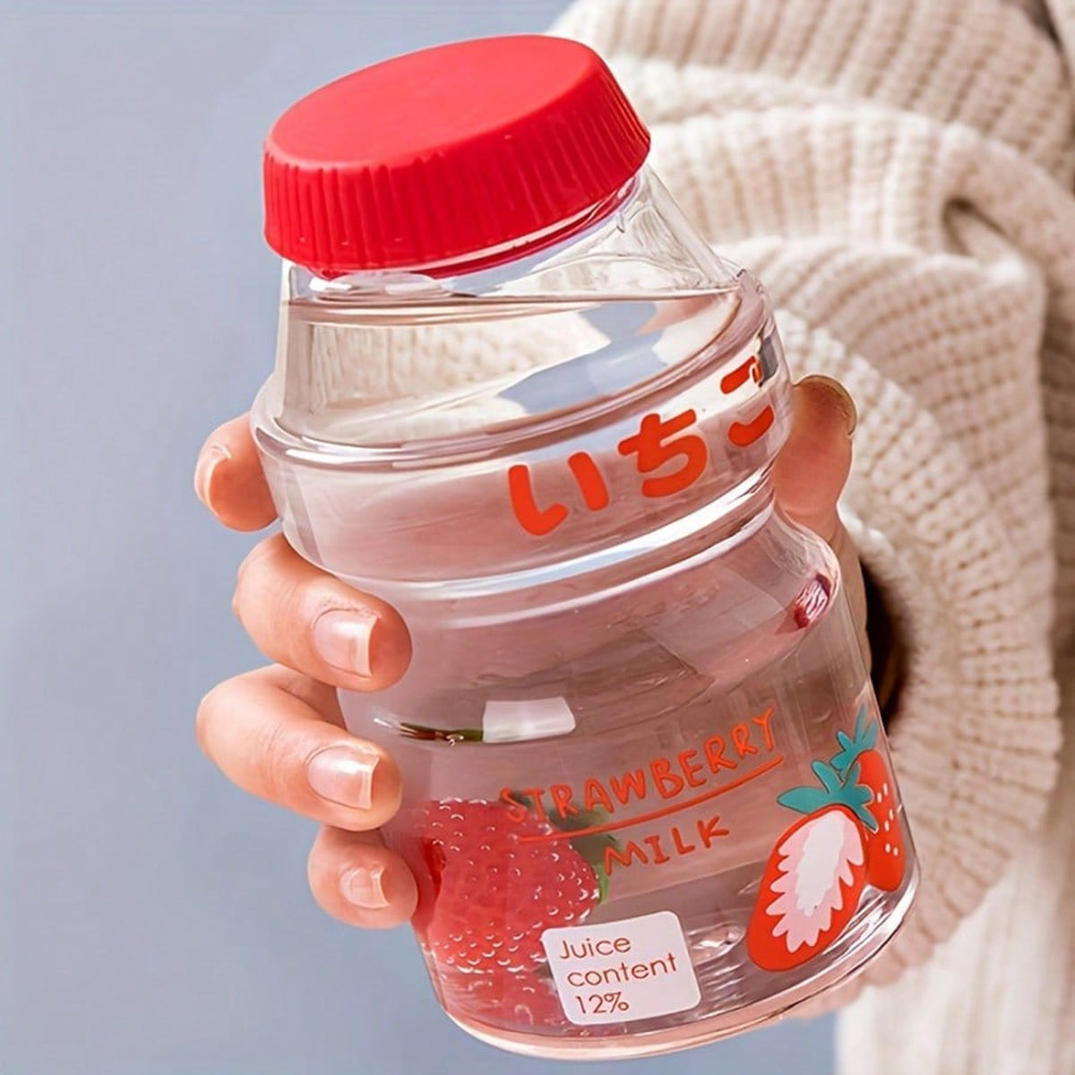 Clear strawberry fruit milk water bottle held in one hand to show its size