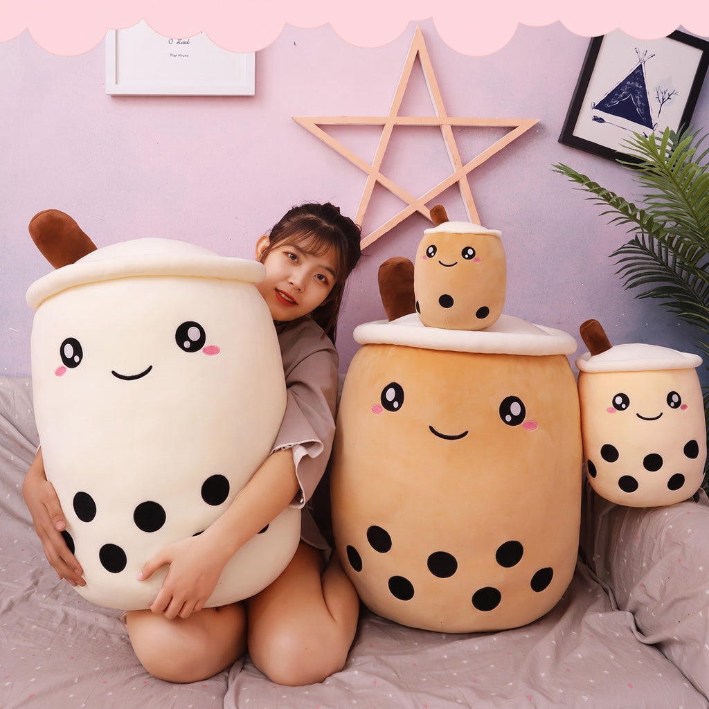 Model seated with a white and a brown Boba Plush Pillow on a bed