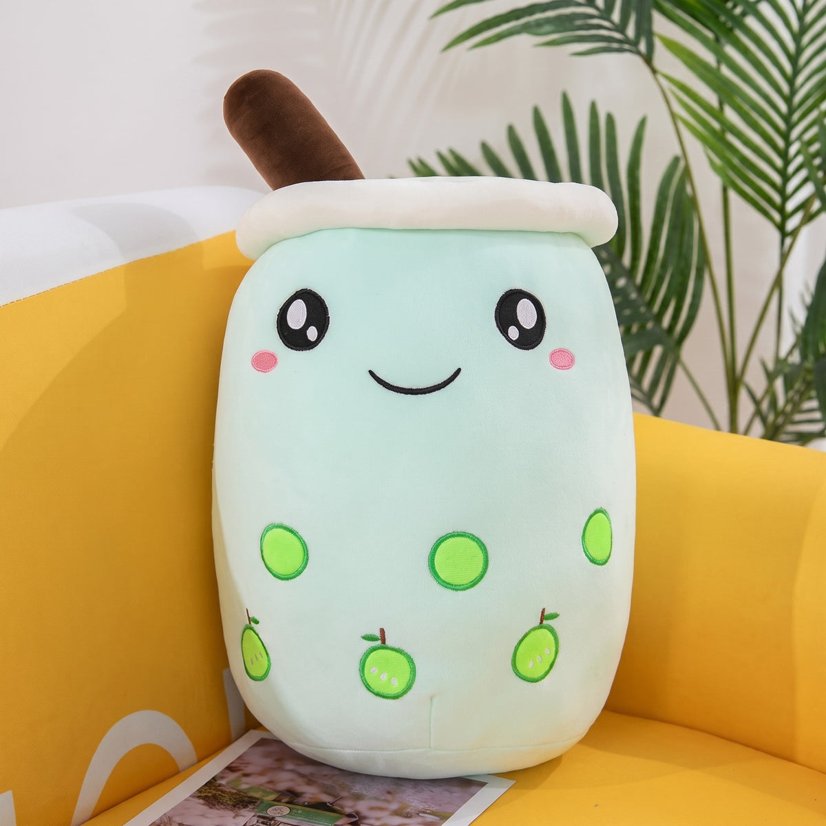 Boba Plush Pillow in mint with fruit prints, wide open eyes and blushing cheeks, a plush bubble-tea cup with a cream lid, straw and pearls