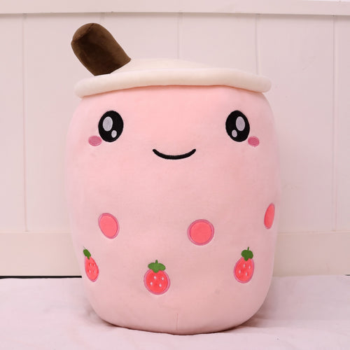 Boba Plush Pillow in pink with strawberry prints, wide open eyes and blushing cheeks, a plush bubble-tea cup with a cream lid, straw and pearls