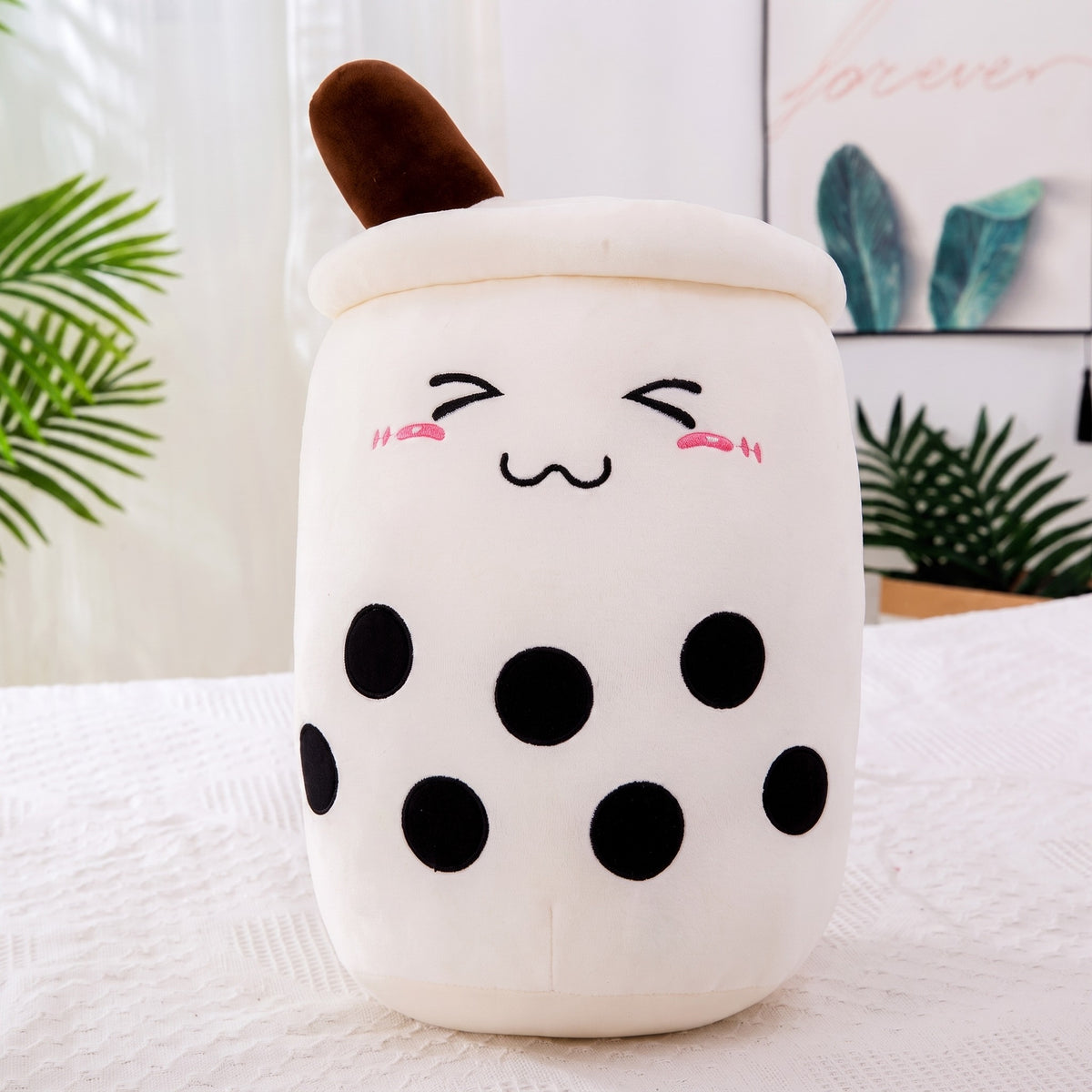 Boba Plush Pillow in white, closed happy eyes and blushing cheeks, a plush bubble-tea cup with a cream lid, straw and pearls