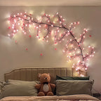 Pink Cherry Blossom Branch Light arching over a headboard above a bed with a teddy bear