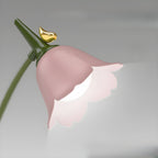 Close-up of the lit flower-shaped lamp head with gold bird, showing the dimming glow