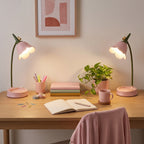 Two Flower LED Desk Lamps in pink, lit, at opposite ends of a desk