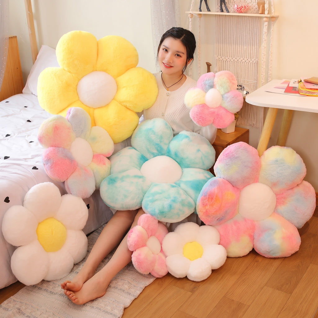 Assorted Flower Plush Pillows in many colors and sizes stacked on a bed, with a model seated among them