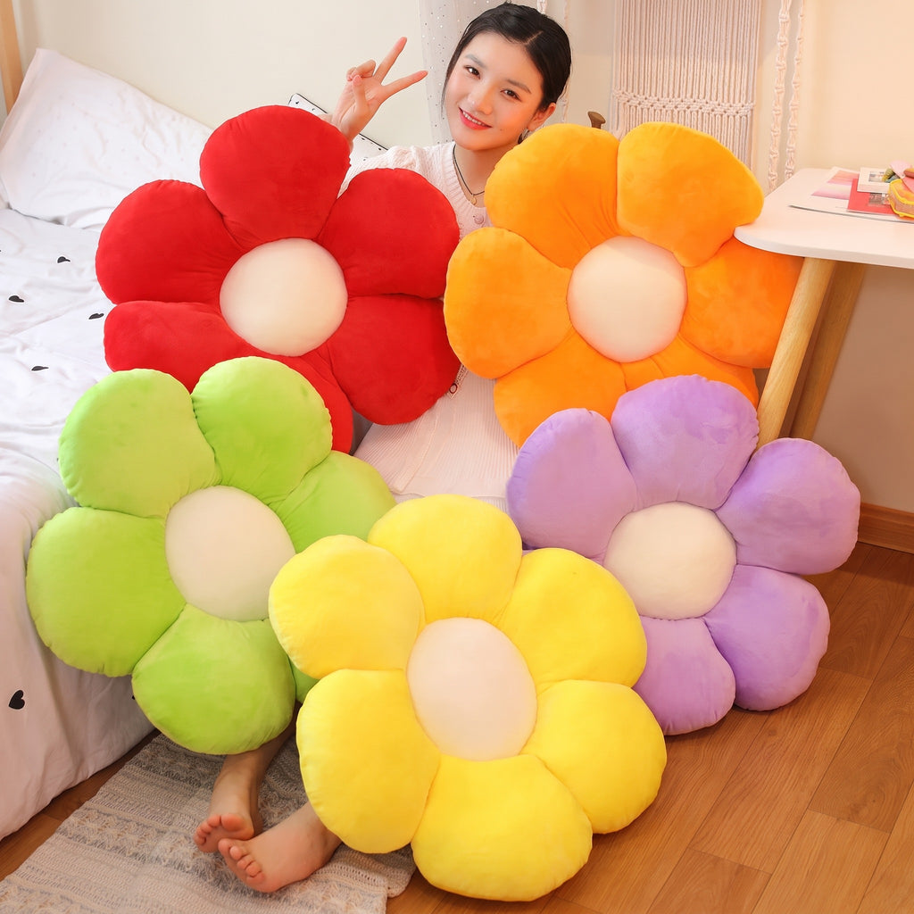 Red, orange, purple, light green and yellow Flower Plush Pillows on a bed, with a model