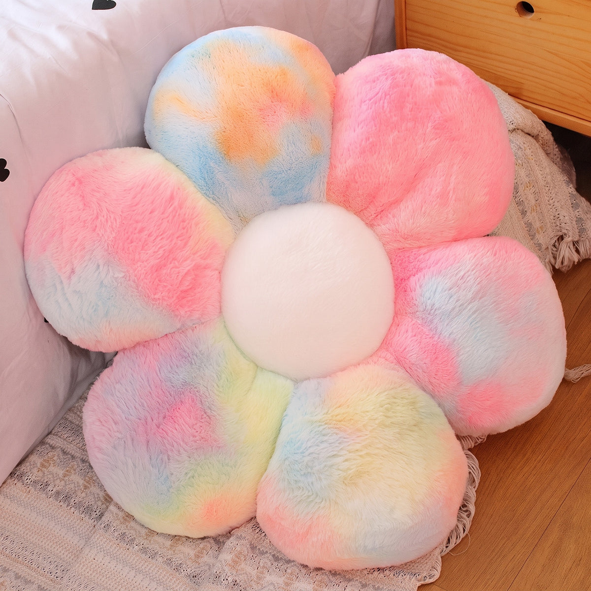 Flower Plush Pillow in fluffy rainbow tie-dye, six plush petals, on a bed