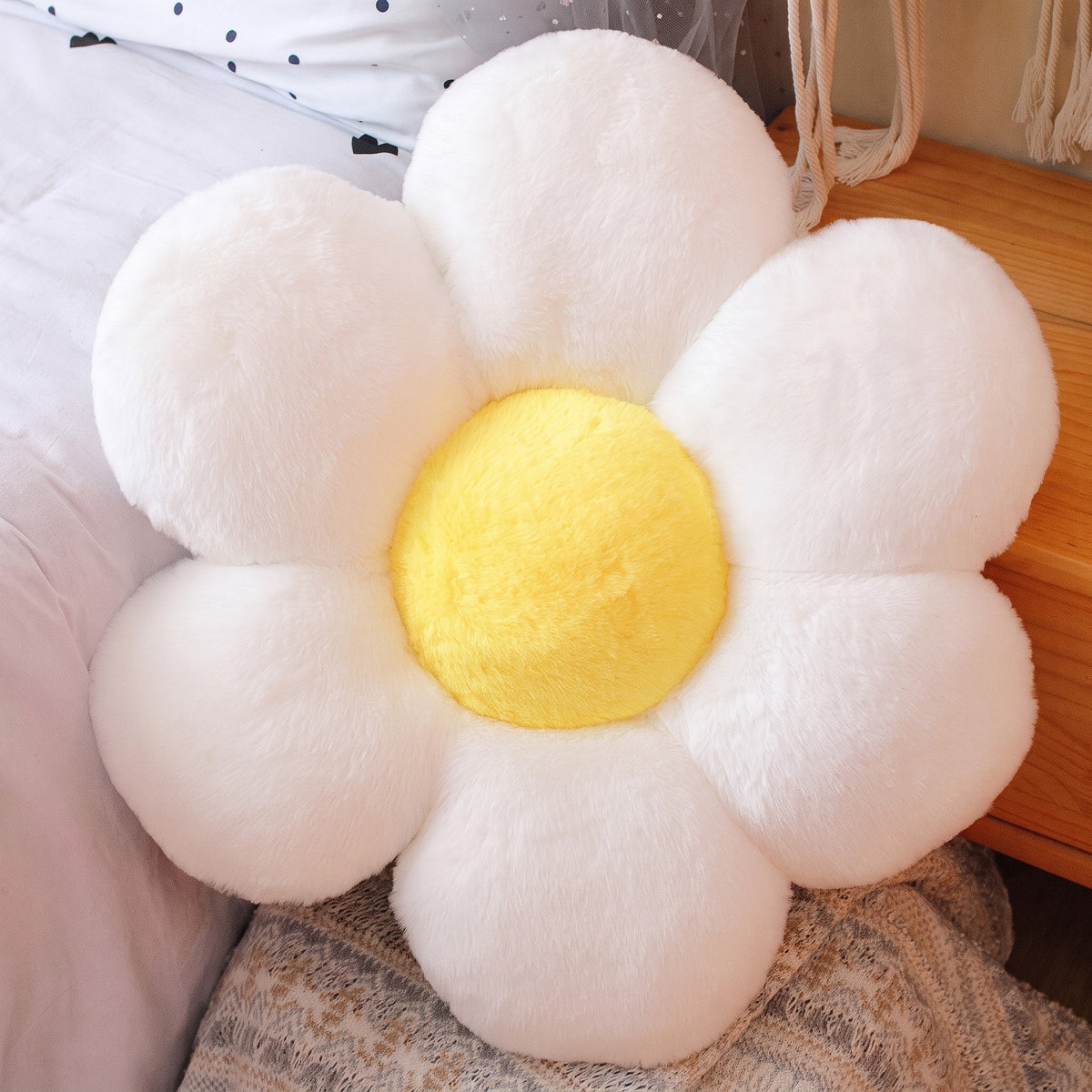 Flower Plush Pillow in fluffy white with a yellow center, six plush petals, on a bed