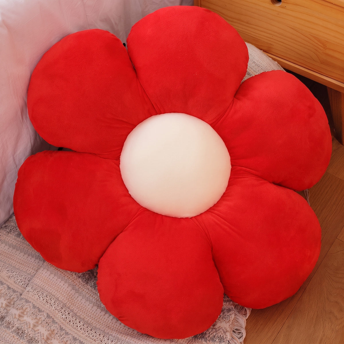 Flower Plush Pillow in red with a cream center, six plush petals, on a bed