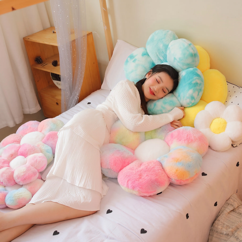 Model lying on a bed with fluffy tie-dye Flower Plush Pillows in blue, pink and white