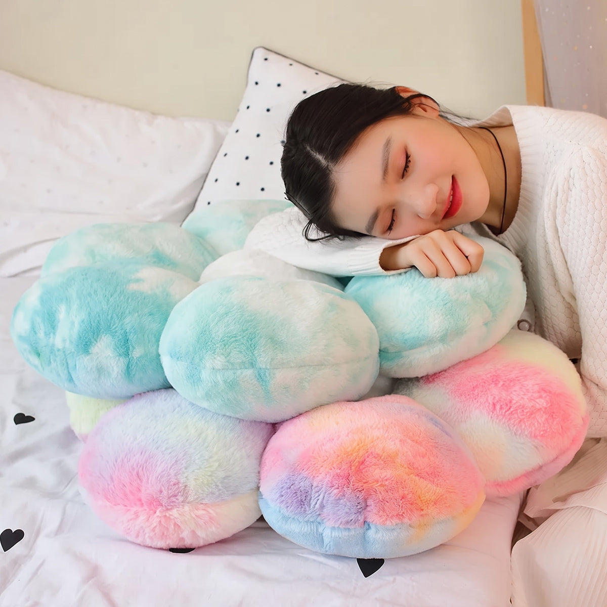 Model resting on a stack of fluffy tie-dye Flower Plush Pillows