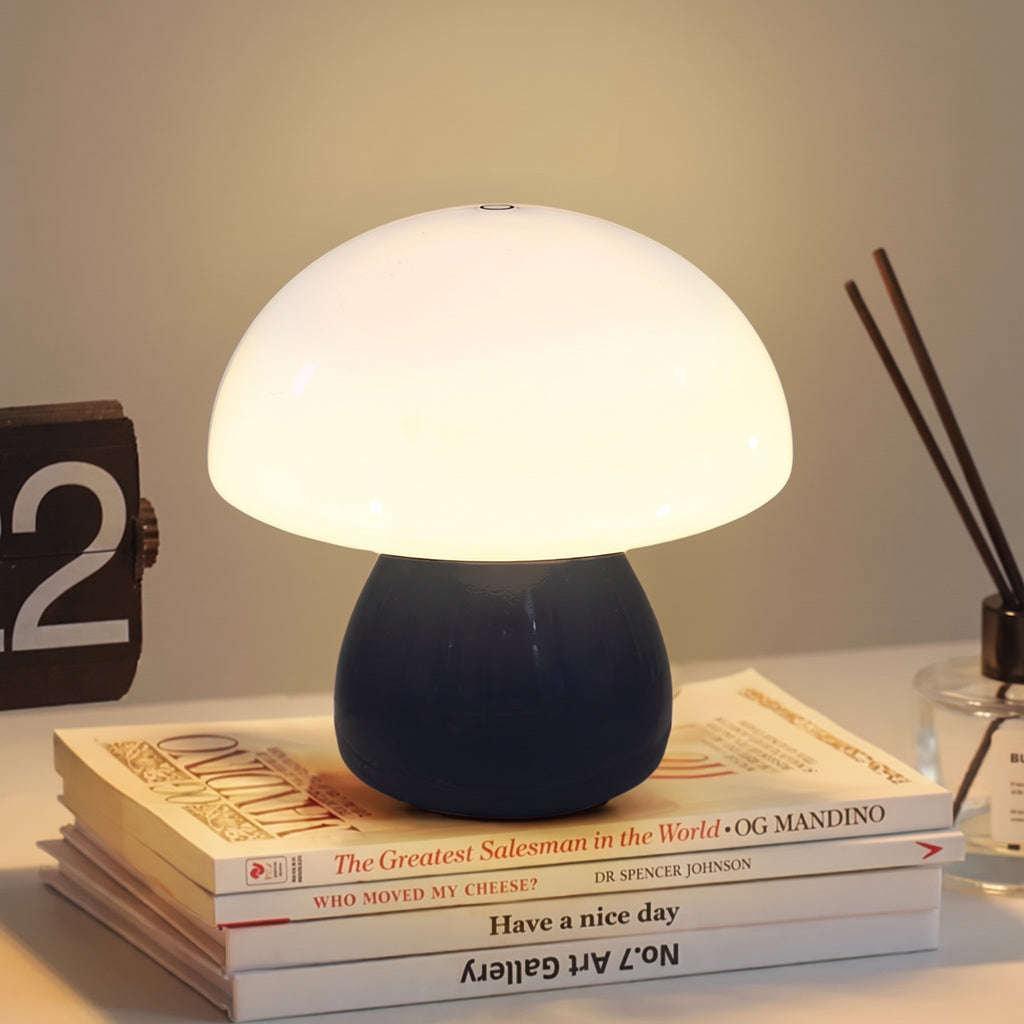 Mini Mushroom Touch Lamp in Black lit warm on a stack of books beside a flip clock