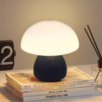 Mini Mushroom Touch Lamp in Black lit warm on a stack of books beside a flip clock