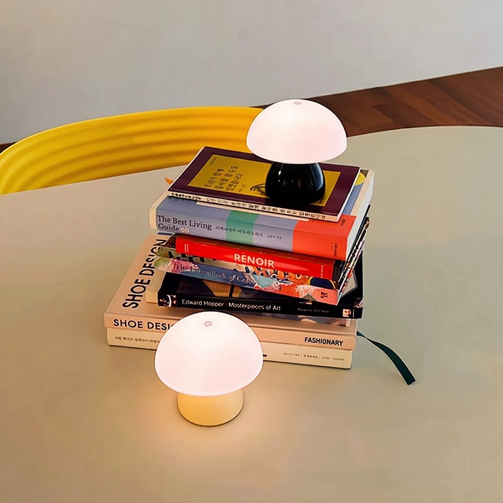 A Pink and a Black Mini Mushroom Touch Lamp lit on books