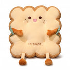 Toast Seat Cushion with the Cheeky face, a plush slice of toast with an embroidered face, small arms and dangling legs, on a white background